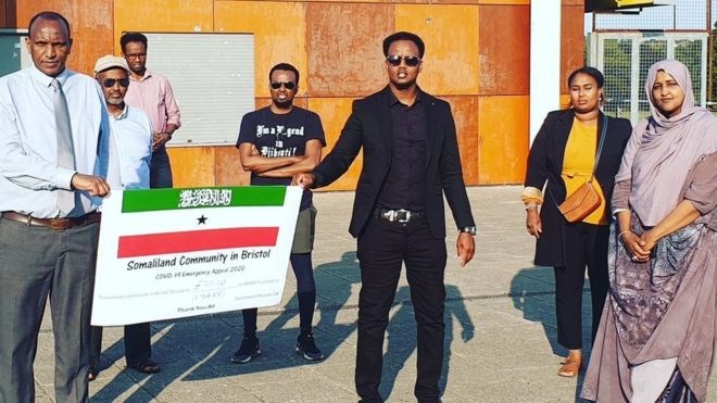 Mohamed Sayaqle (centre), Said Burale (2nd left), Nura Aabe (far right) and other volunteers present Kaysar Mohamed from the Somaliland Mission UK with the cheque