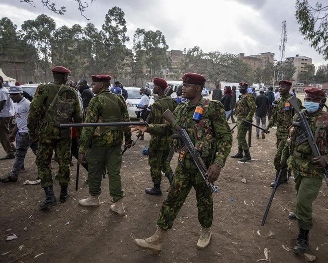 A police officer gestures indicating people to get back as police try to push back an angry crowd, after a few ballot boxes were discovered with their seals broken, at a tallying center in the Mathare area of Nairobi, Kenya Wednesday, Aug. 10, 2022. Kenyans are waiting for the results of a close presidential election in which the turnout was lower than usual.  BEN CURTIS / AP PHOTO